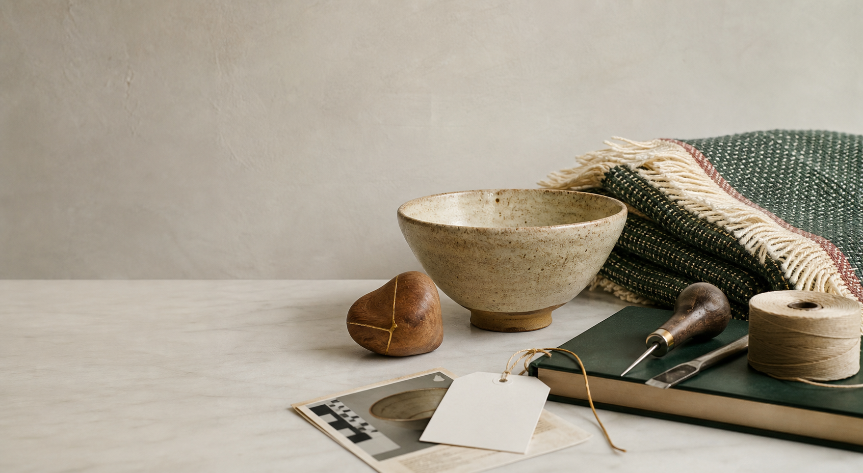Illustrative studio still life with a handmade ceramic bowl, textile and craft tools.